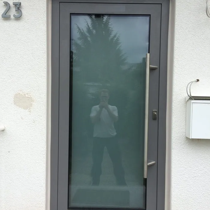 Breites Fenster mit dunklem Rahmen in verputzter Fassade
