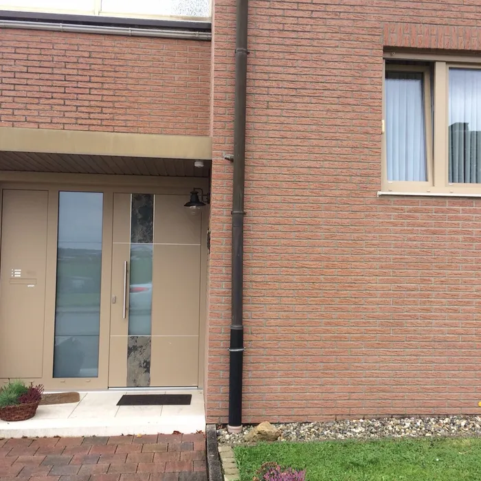 Beige Haustür mit Lichtausschnitt in einer Klinkerfassade