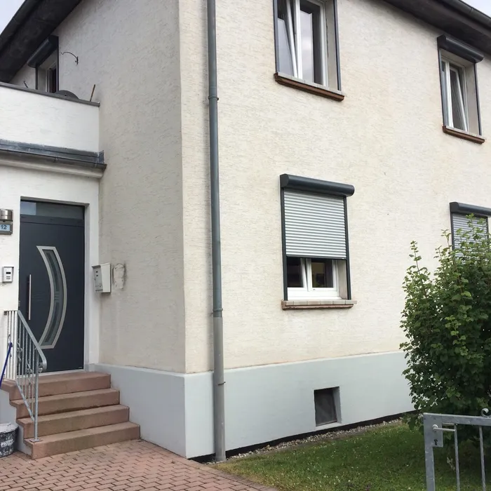 Anthrazitfarbene Haustür an einem weiß verputzten Haus mit Außentreppe