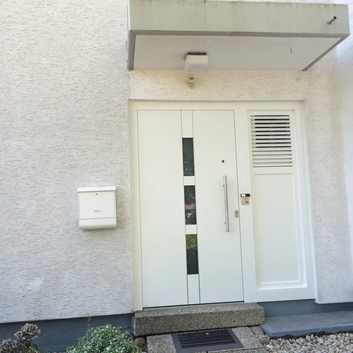 Weiße Haustür mit Lüftungsgitter